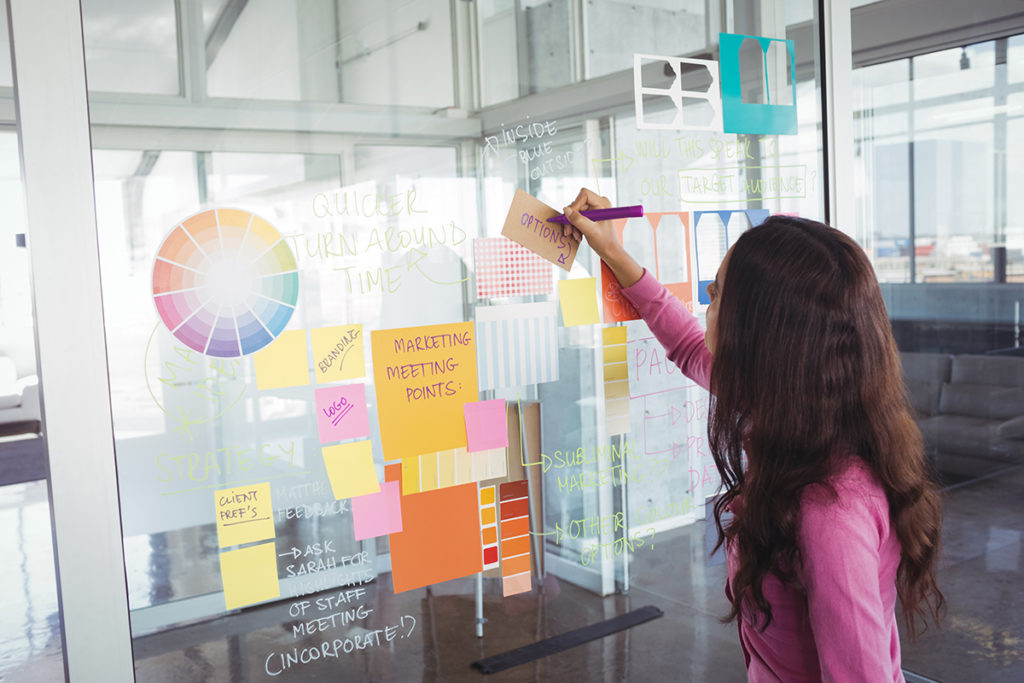 woman at a whiteboard making notes about marketing strategy