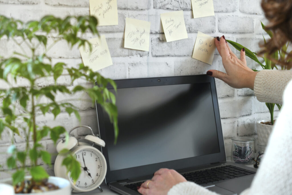 Individual with open laptop and sticky notes doing content calendar planning