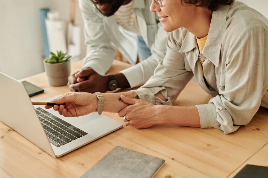 Two professionals collaborating at a laptop, discussing strategies to improve SEO for small companies.
